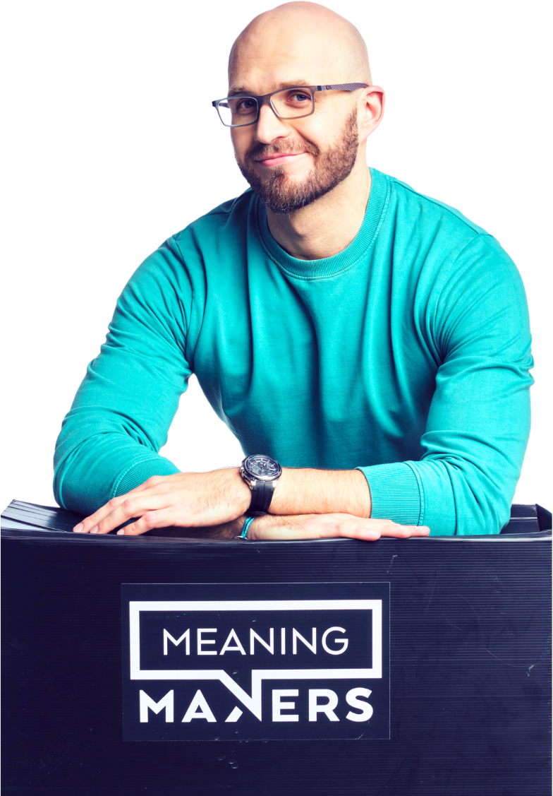 Wojciech Mendyka in a turquoise sweater, leaning on a Meaning Makers box